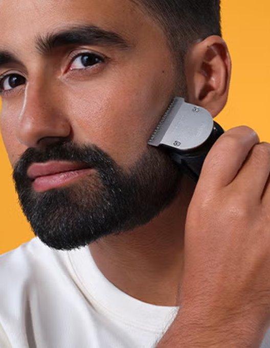 a man with a beard shaving his face with an electric razor